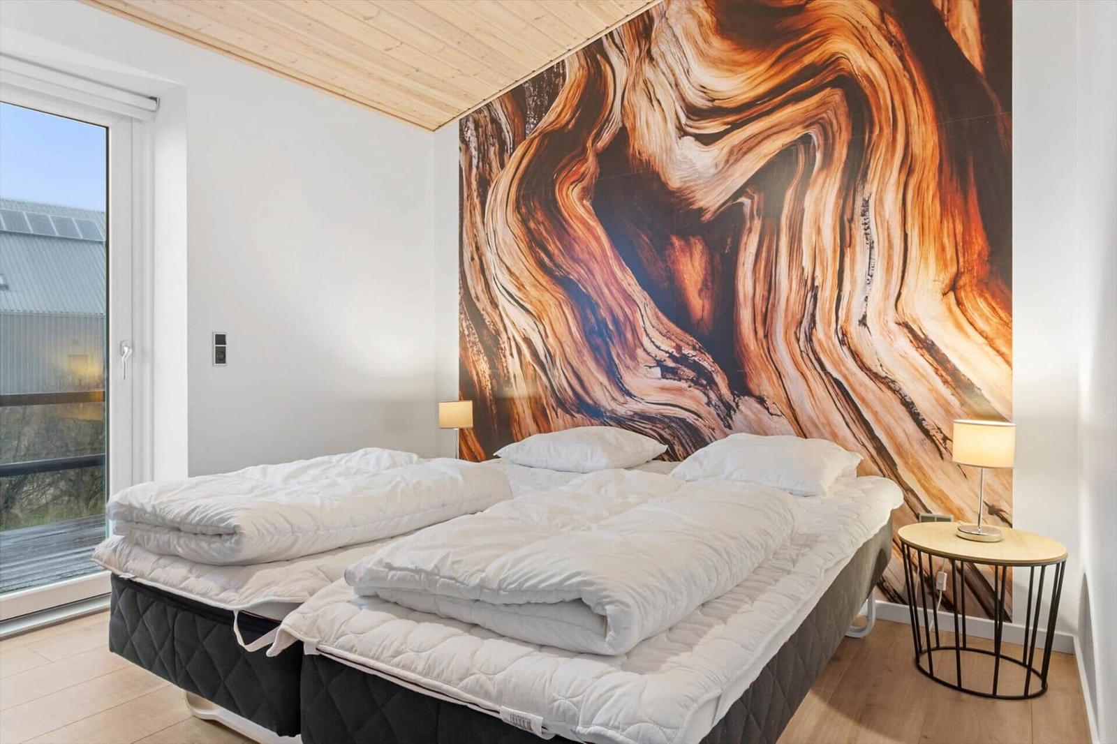 Room with double bed, wall mural, and window with view.