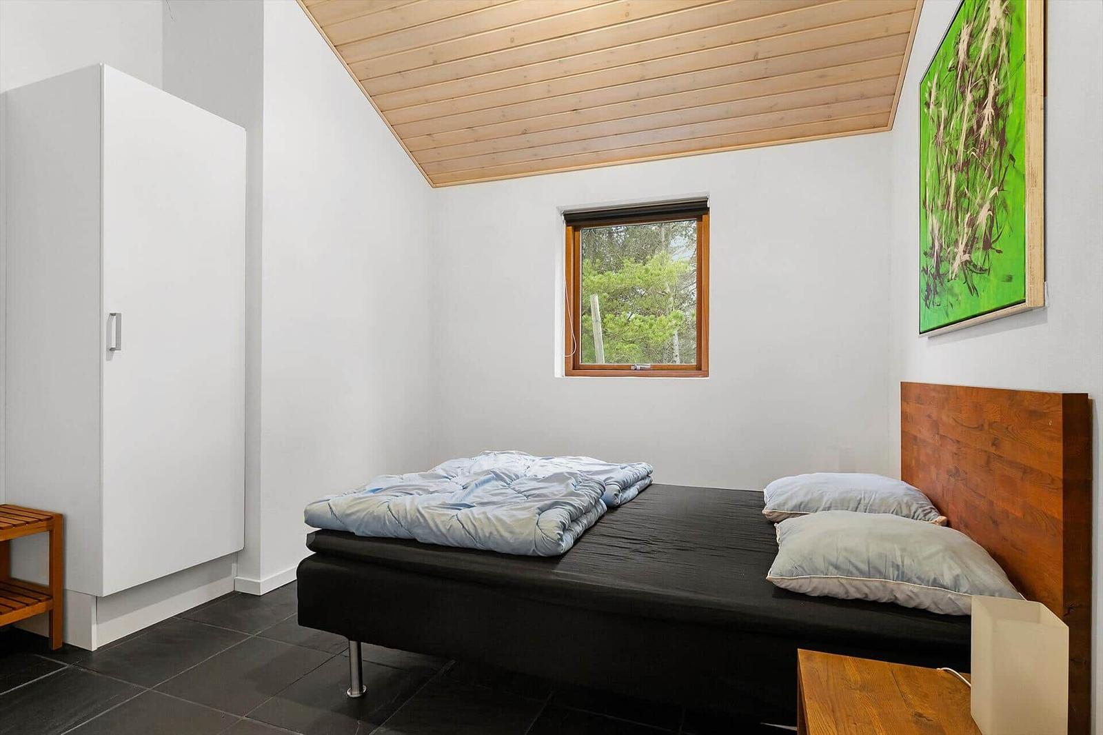 Bedroom with bed, wardrobe, and window to the forest.