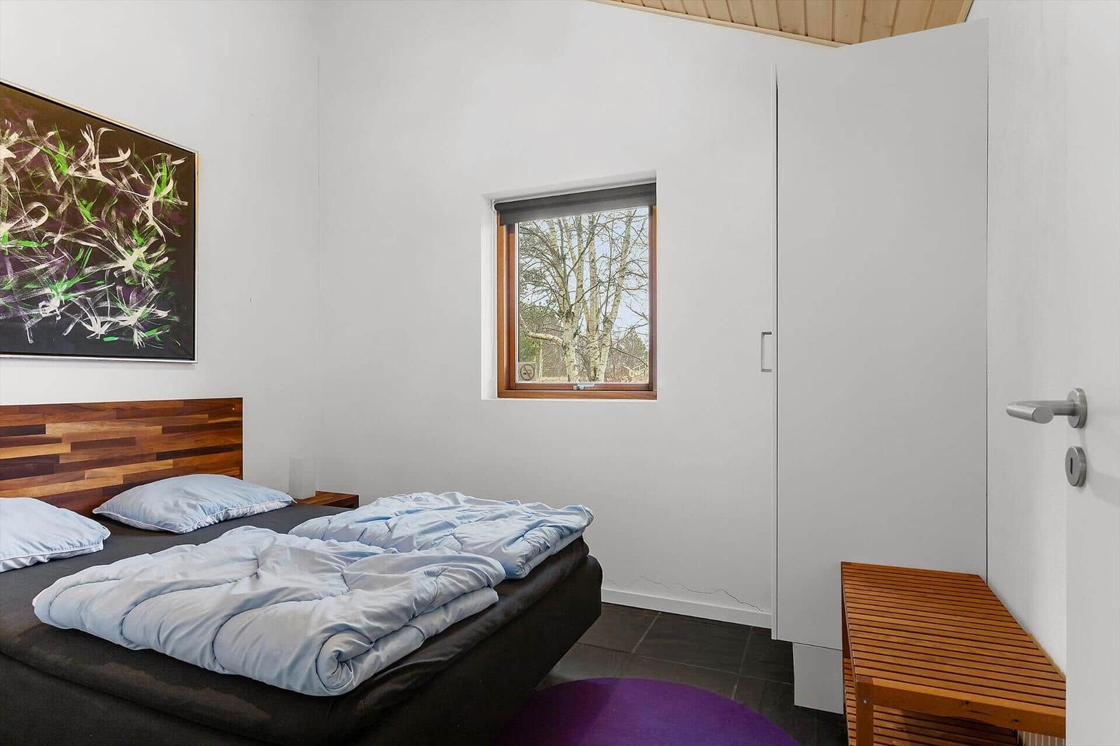 Bedroom with bed, wall art, and window for tree view.