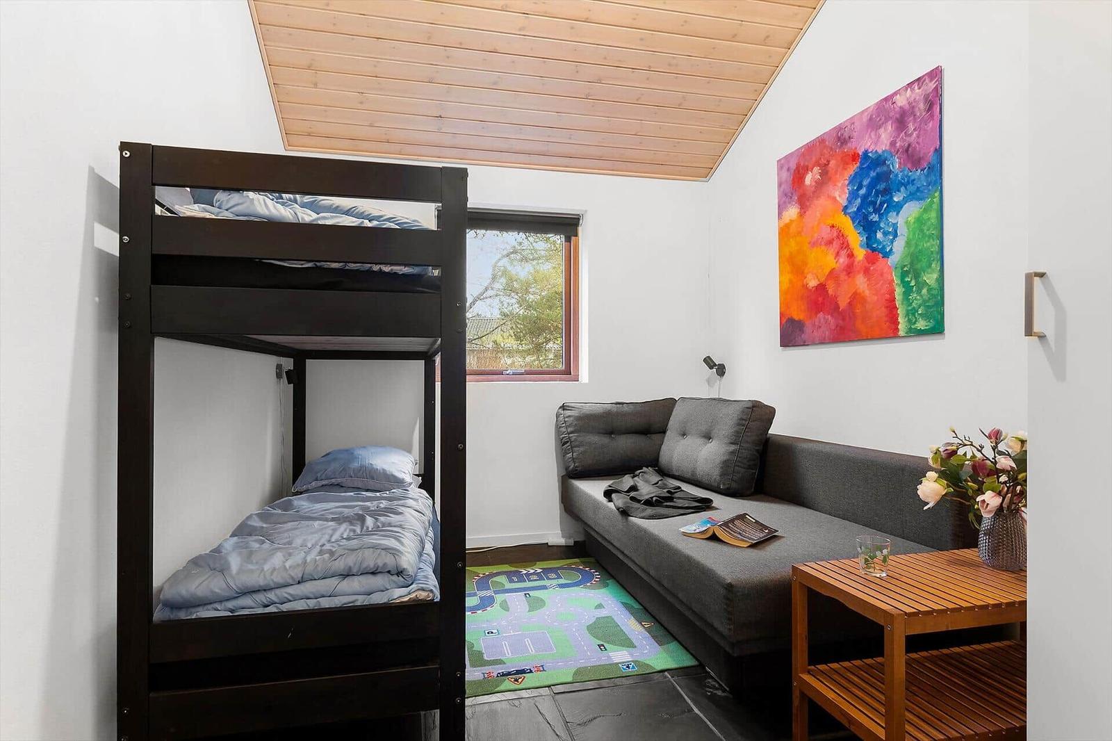 Room with bunk bed, sofa, and colorful wall art.