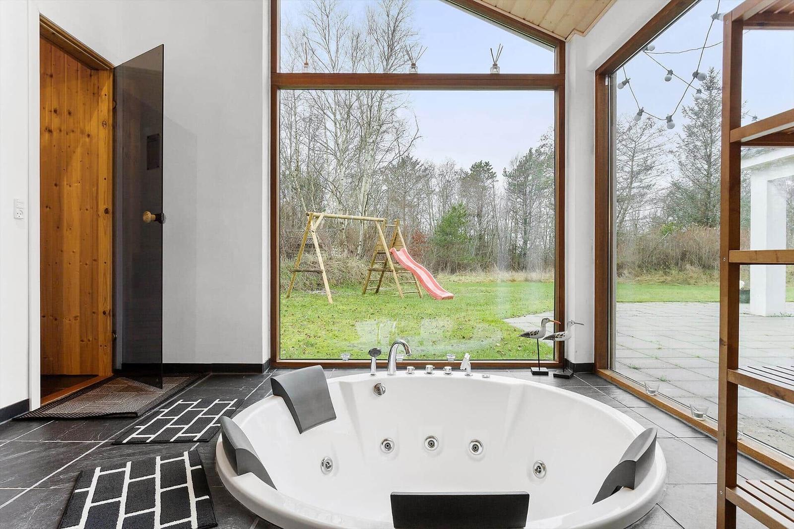 Jacuzzi with view of garden featuring slide and play equipment.
