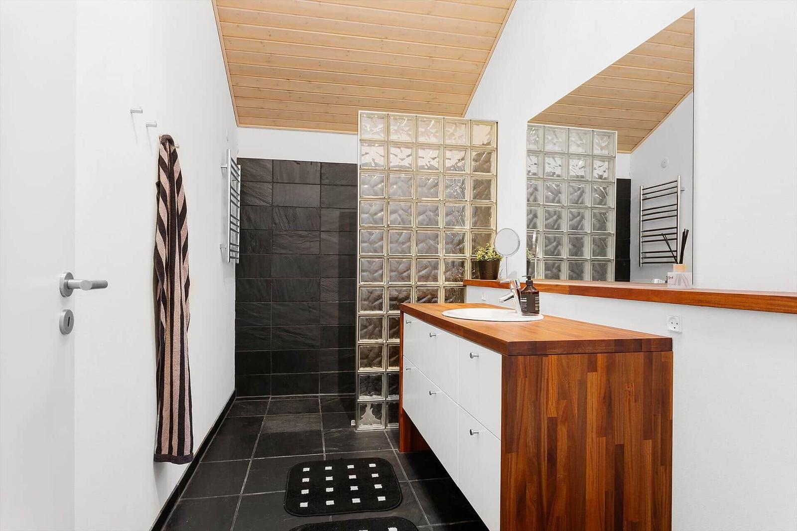 Bathroom with wooden ceiling, glass block wall, and wooden vanity.