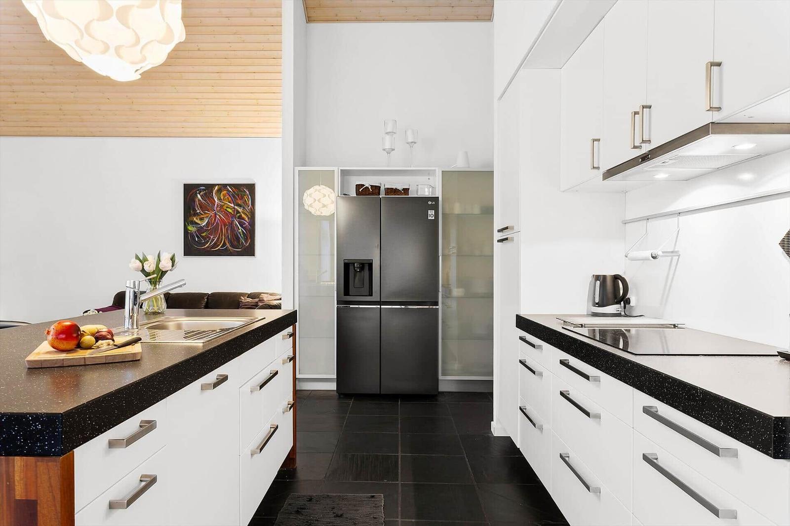 Kitchen with white cabinets, black countertops, and stainless steel refrigerator.