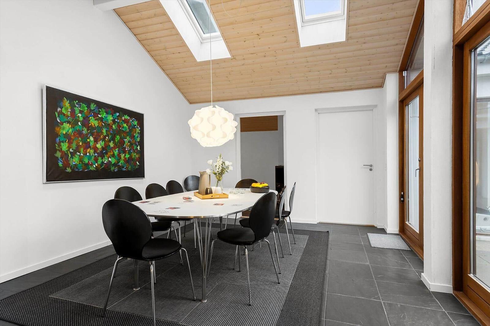 Dining room with table, chairs, skylights, and wall art.