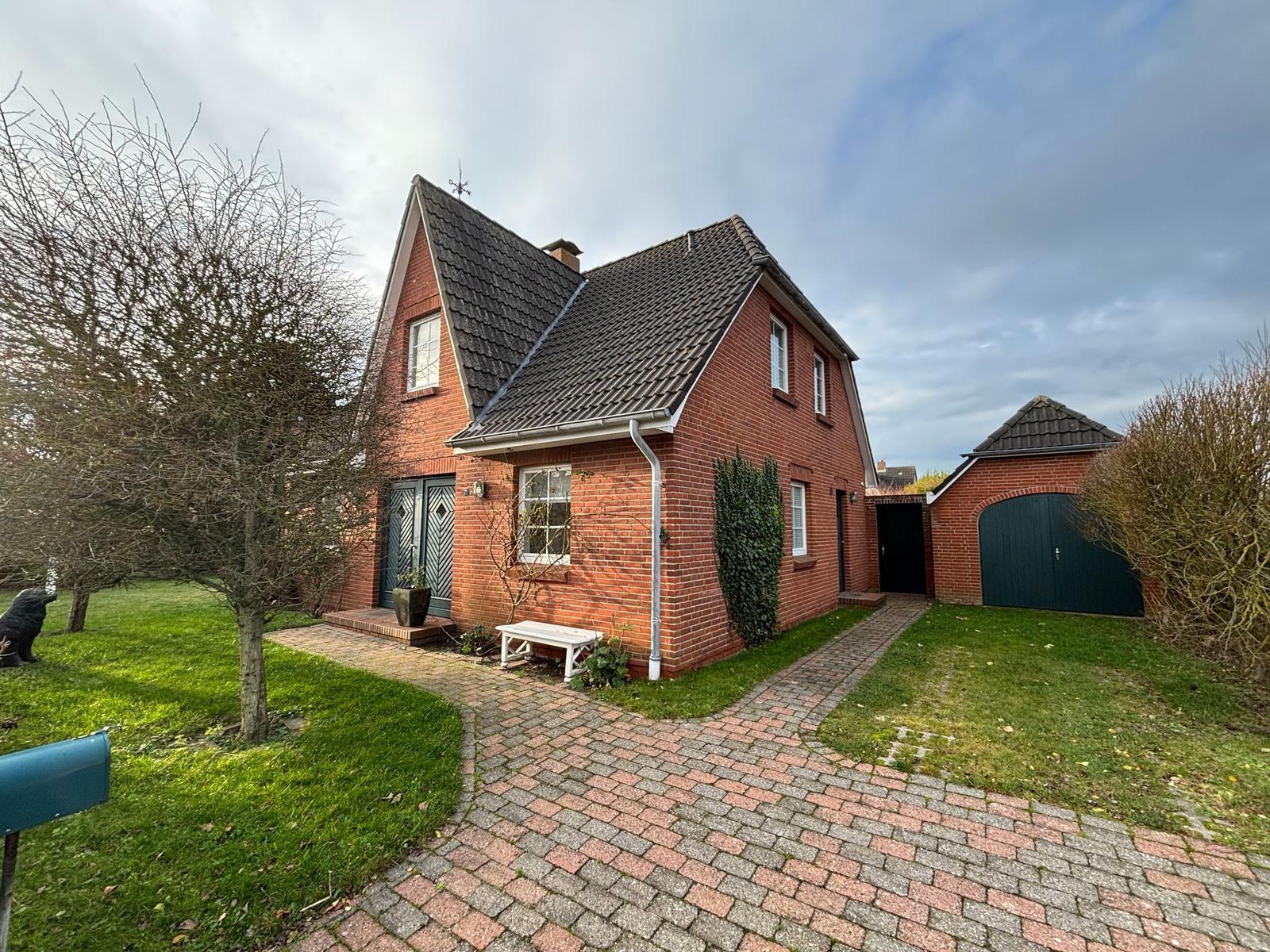 Rotes Backsteinhaus mit Garage, gepflasterter Weg und grünem Rasen.
