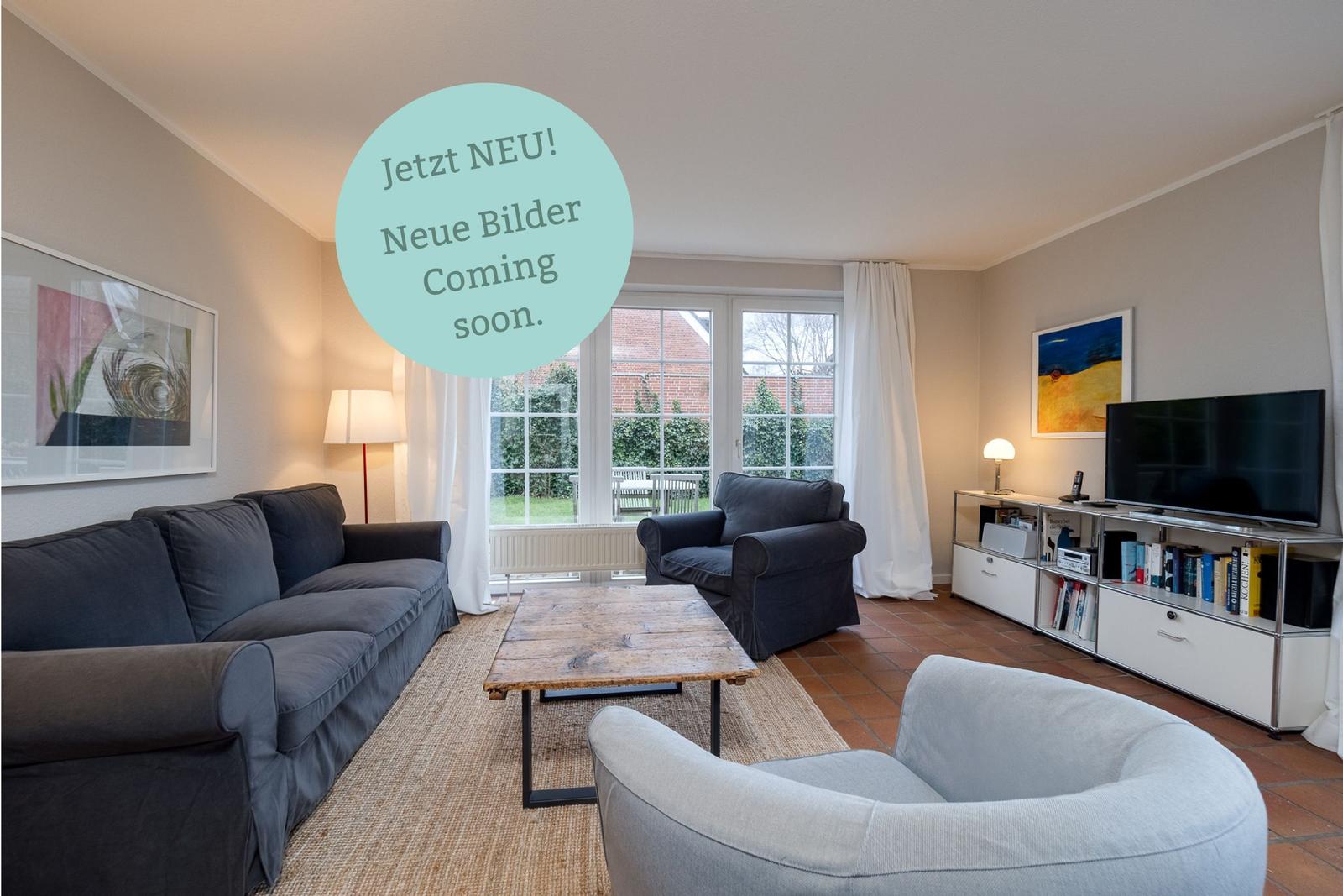 Wohnzimmer mit Sofa, Sessel und Fernseher. Durchgang zum Garten.