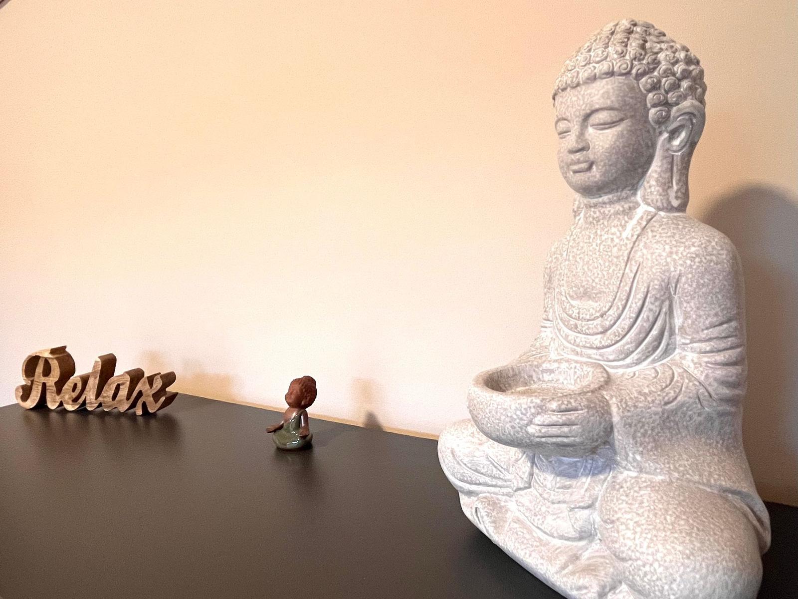 Buddha-Statue mit kleinem Figuren-Set auf dunklem Tisch