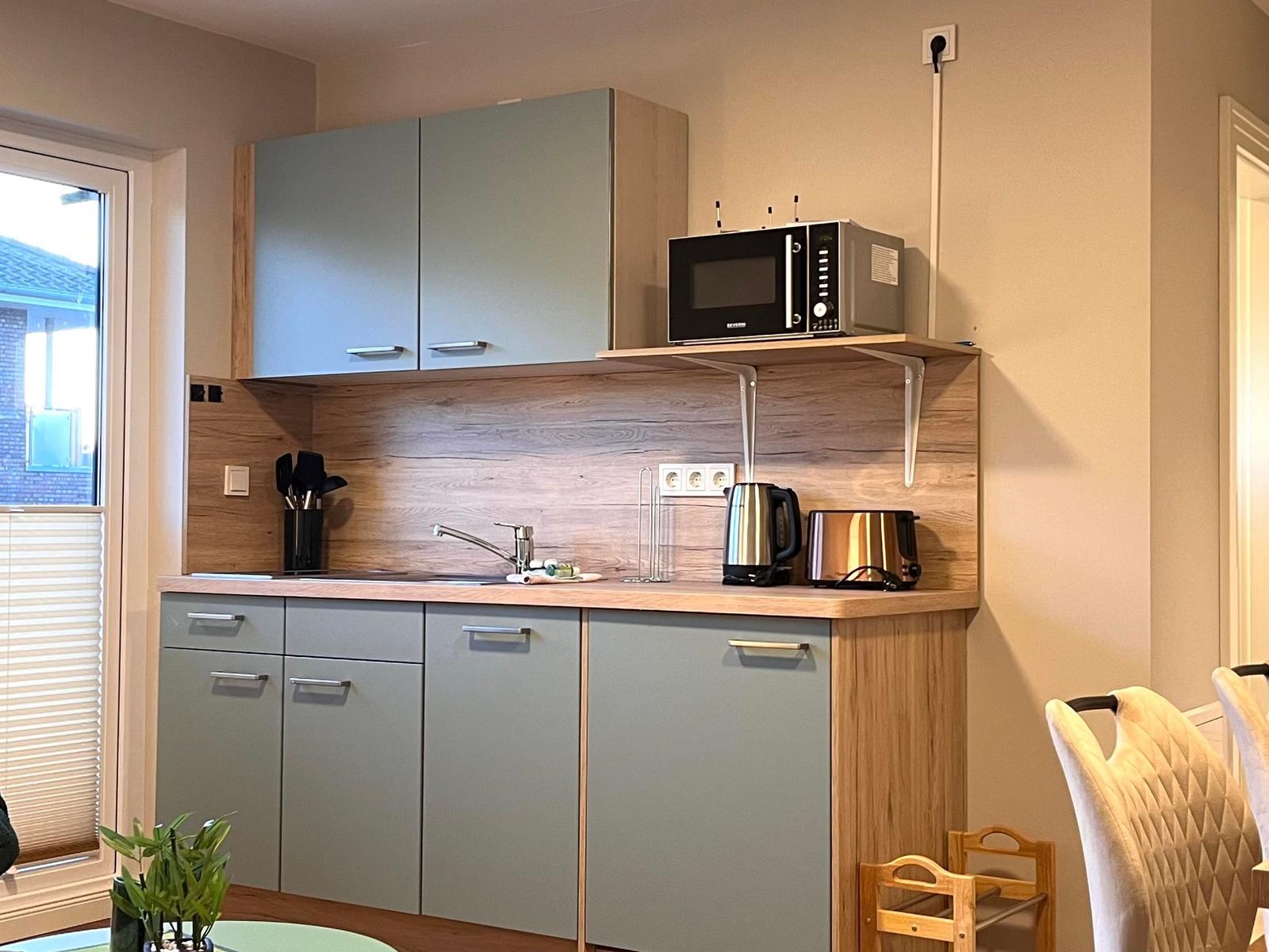 Küche mit Arbeitsplatte, Spüle, Mikrowelle, Kaffeemaschine und Toaster.