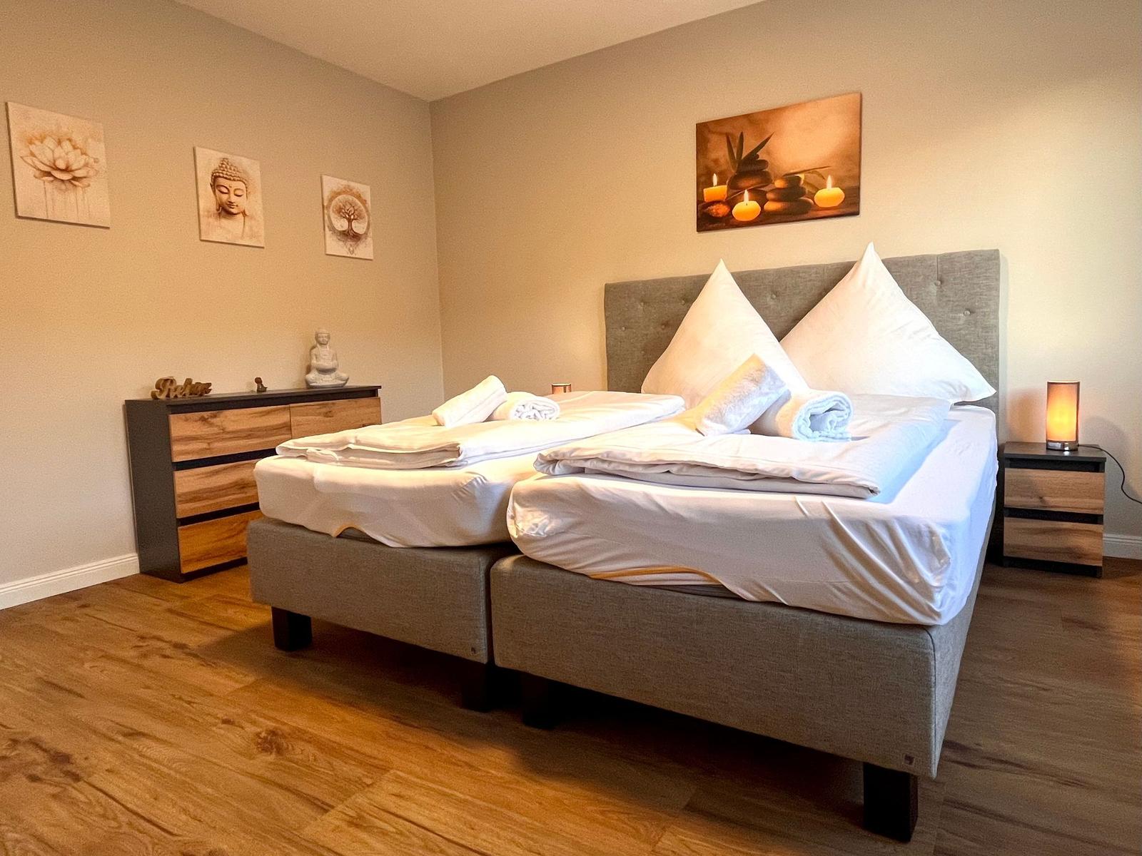 Schlafzimmer mit Doppelbett, Nachttischen und Wandbildern.