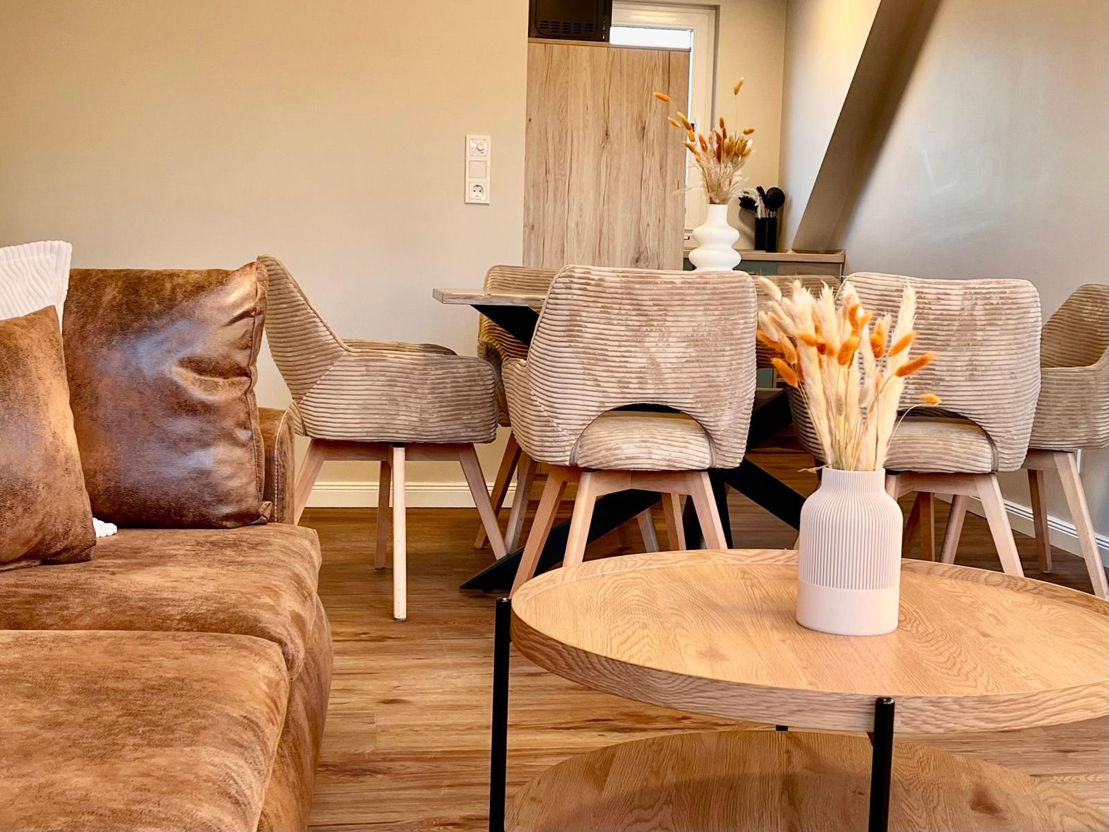 Wohn- und Essbereich mit Sofa, Stühlen und Tisch. Holzfußboden und Dekorationsgegenstände.