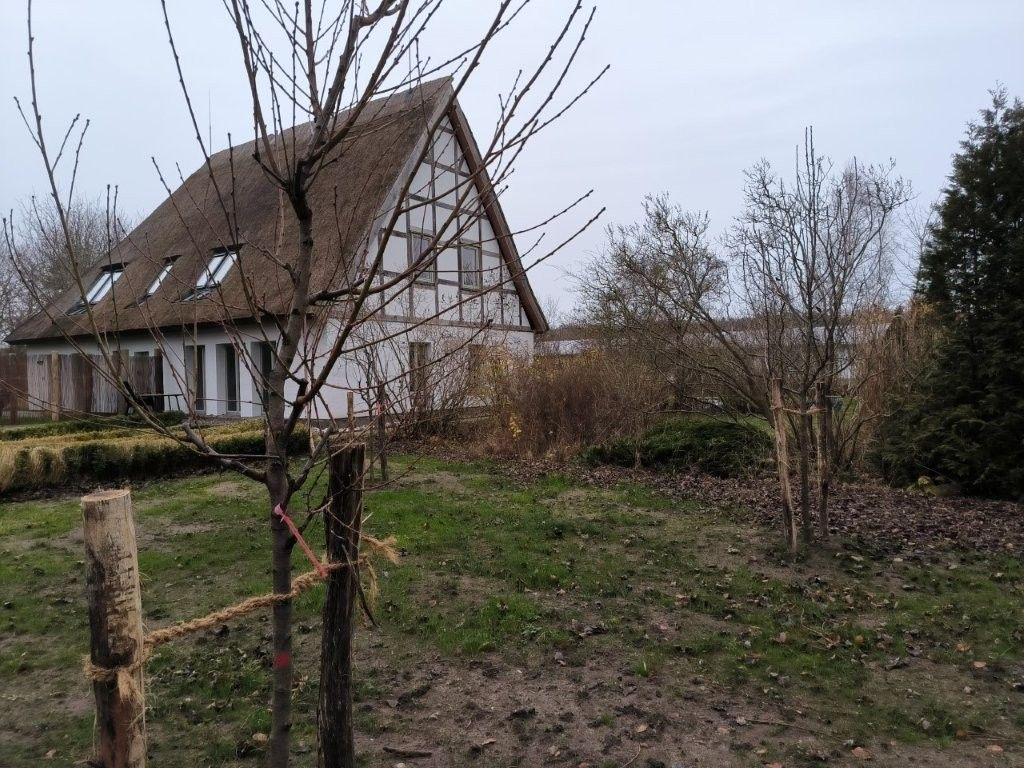 Haus mit strohgedecktem Dach und Garten im Vordergrund.