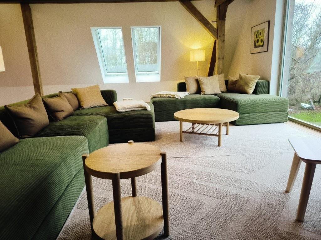 Grüner Sofa-Set mit Holztischen und großen Fenstern im Wohnzimmer.