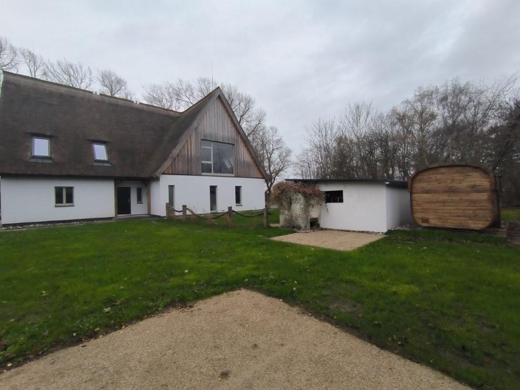 Haus mit Dach und Garten. Nebengebäude und Holztor sichtbar.