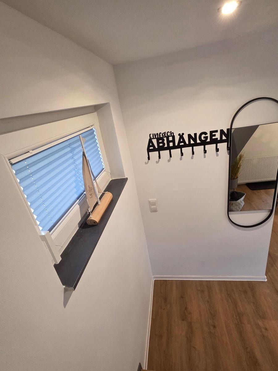 Eingangsbereich mit Spiegel, Kleiderhaken und Fenster mit Segelbootmodell.