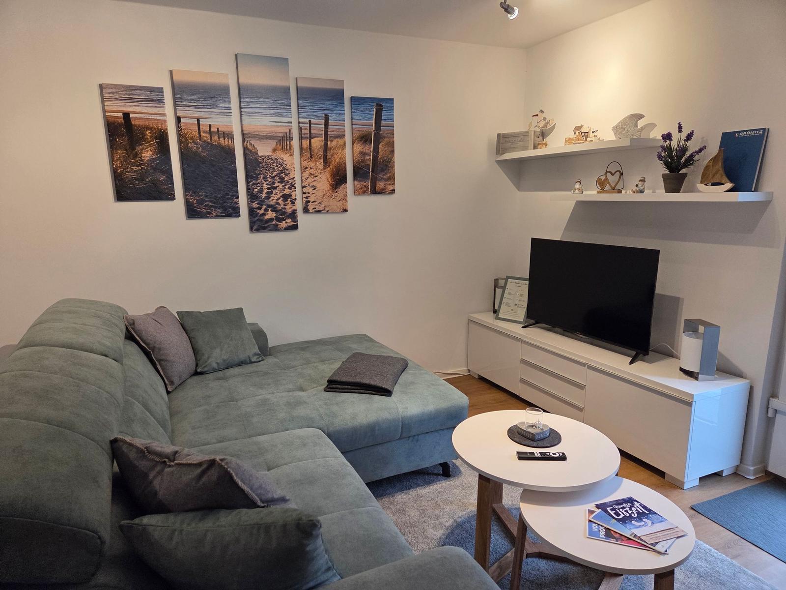 Wohnzimmer mit Sofa, TV und Wandbildern