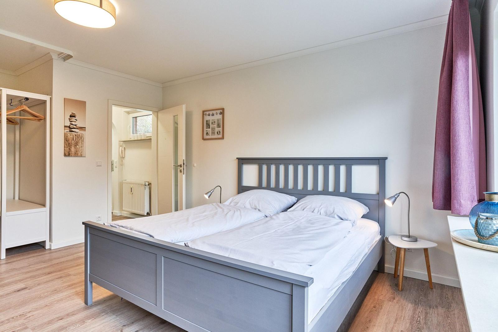 Schlafzimmer mit Doppelbett, Kleiderschrank und Nachttisch mit Lampe.