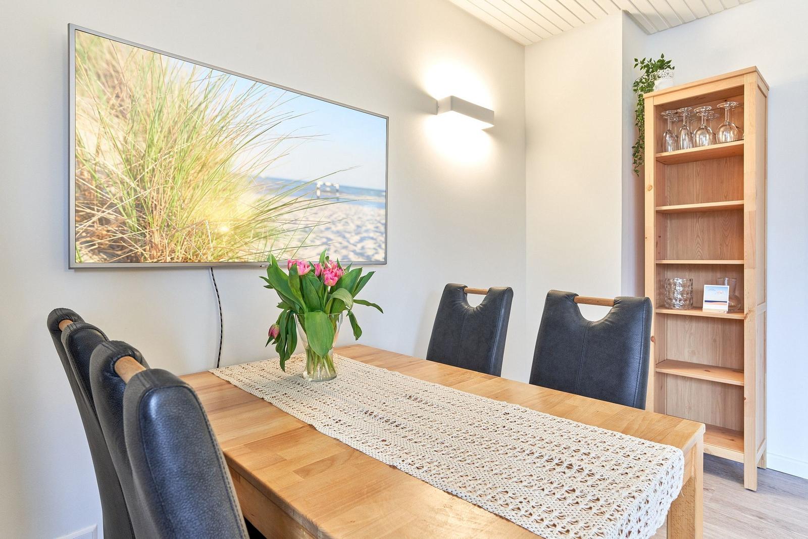 Esszimmer mit Holztisch, Stühlen und Bild an der Wand.