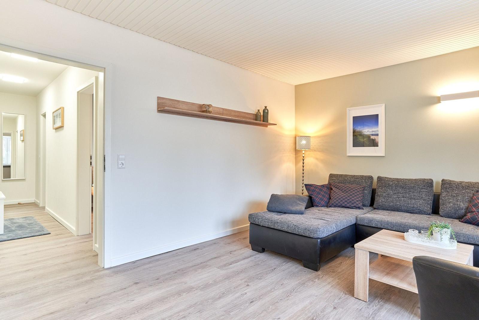 Wohnzimmer mit Sofa, Couchtisch und Holzregal an der Wand.