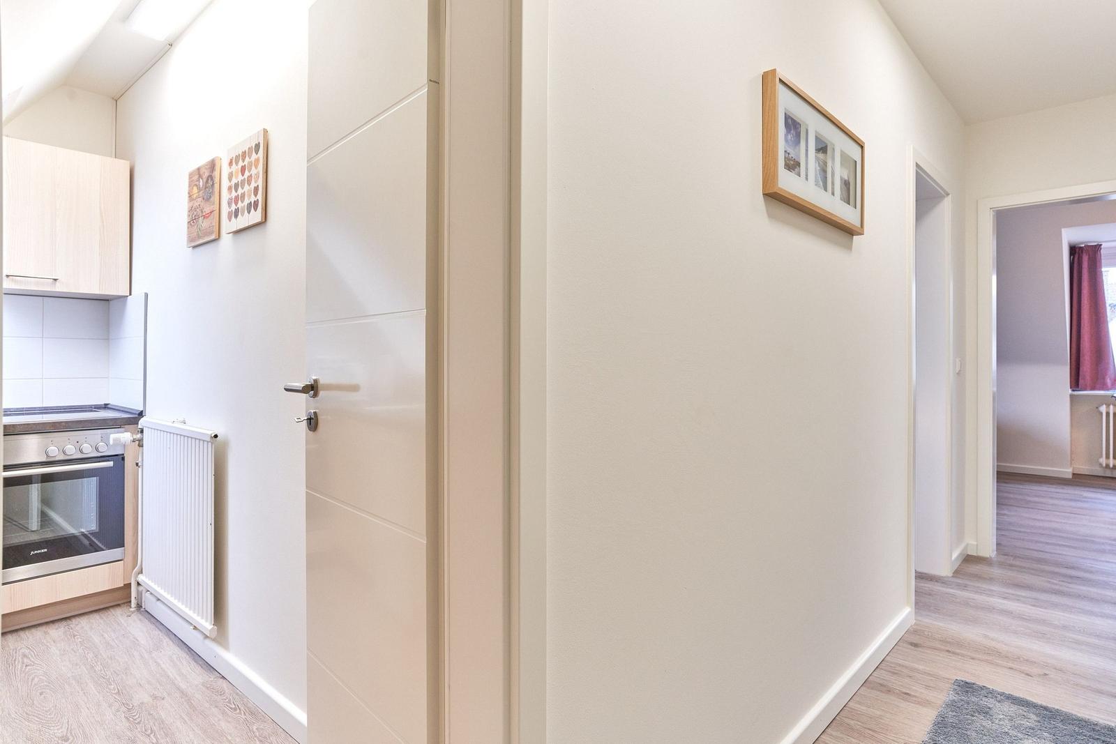 Flur mit Tür, Wandbild und Blick in Küche und Wohnzimmer