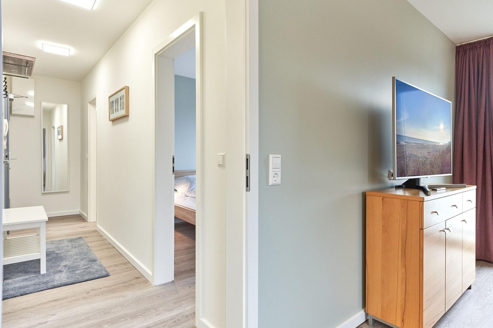 Flur mit Schlafzimmer und TV-Schrank mit Fernseher.