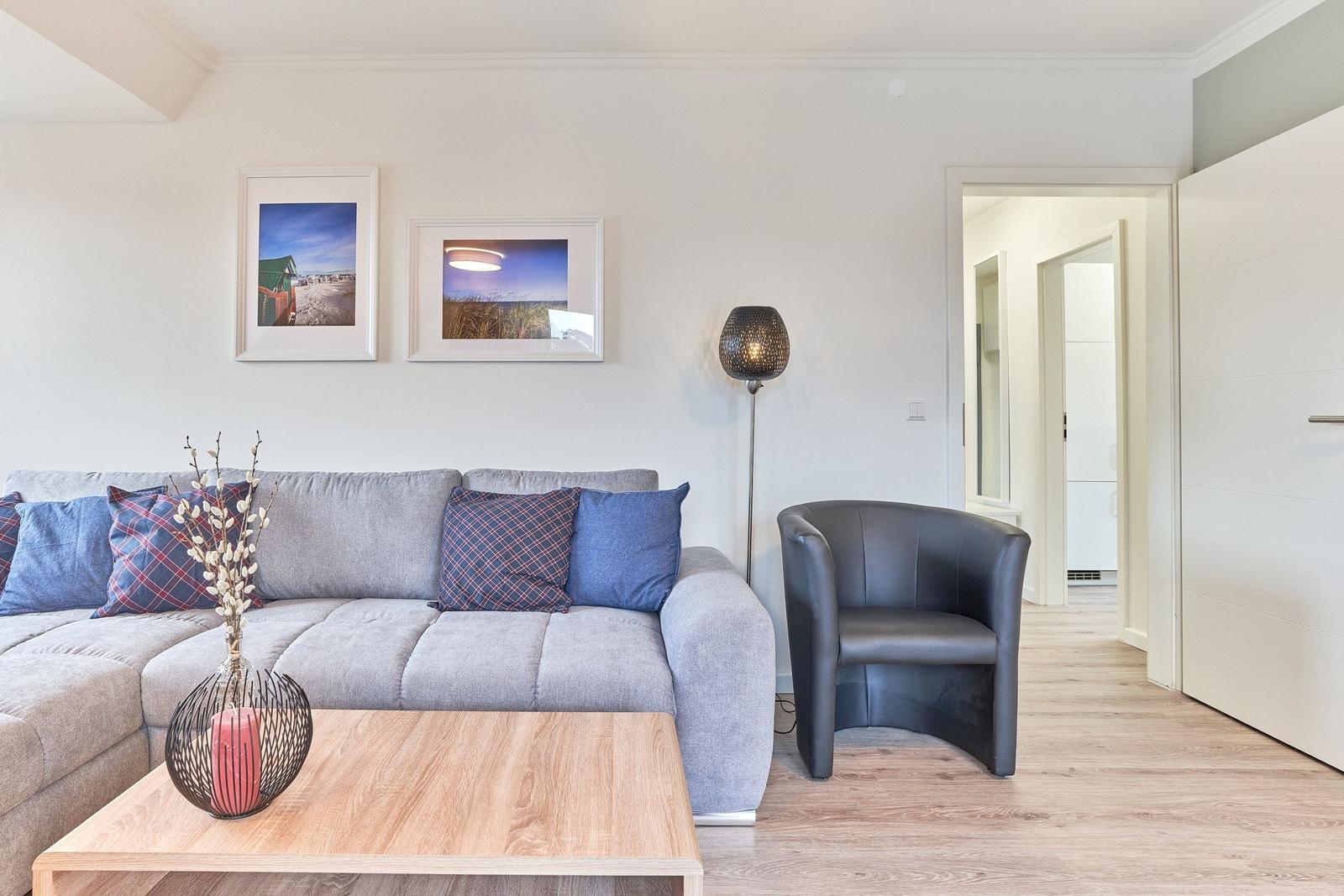 Ein Wohnzimmer mit grauem Sofa, Holztisch und schwarzer Sessel.
