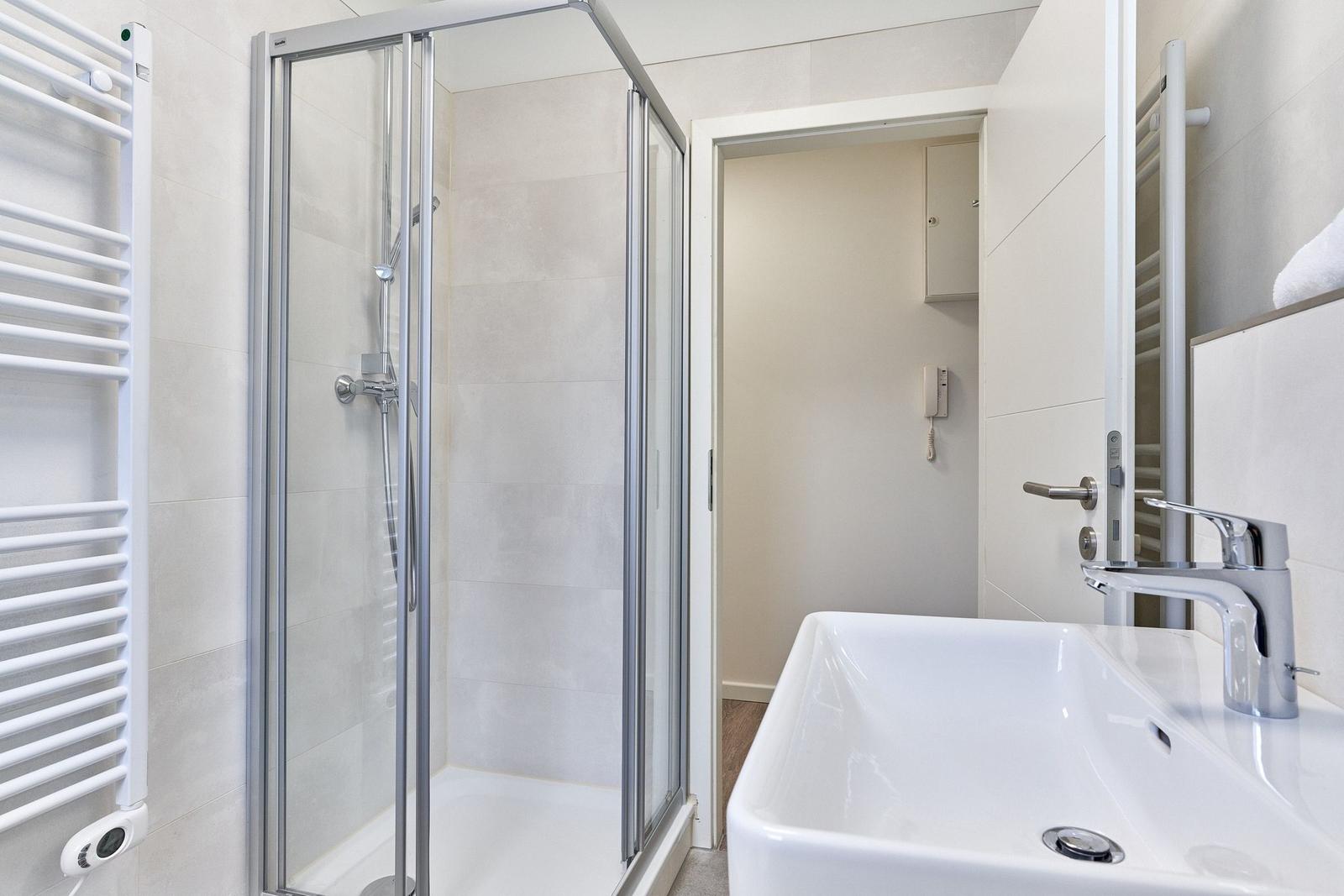 Badezimmer mit Dusche, Waschbecken und Heizkörper