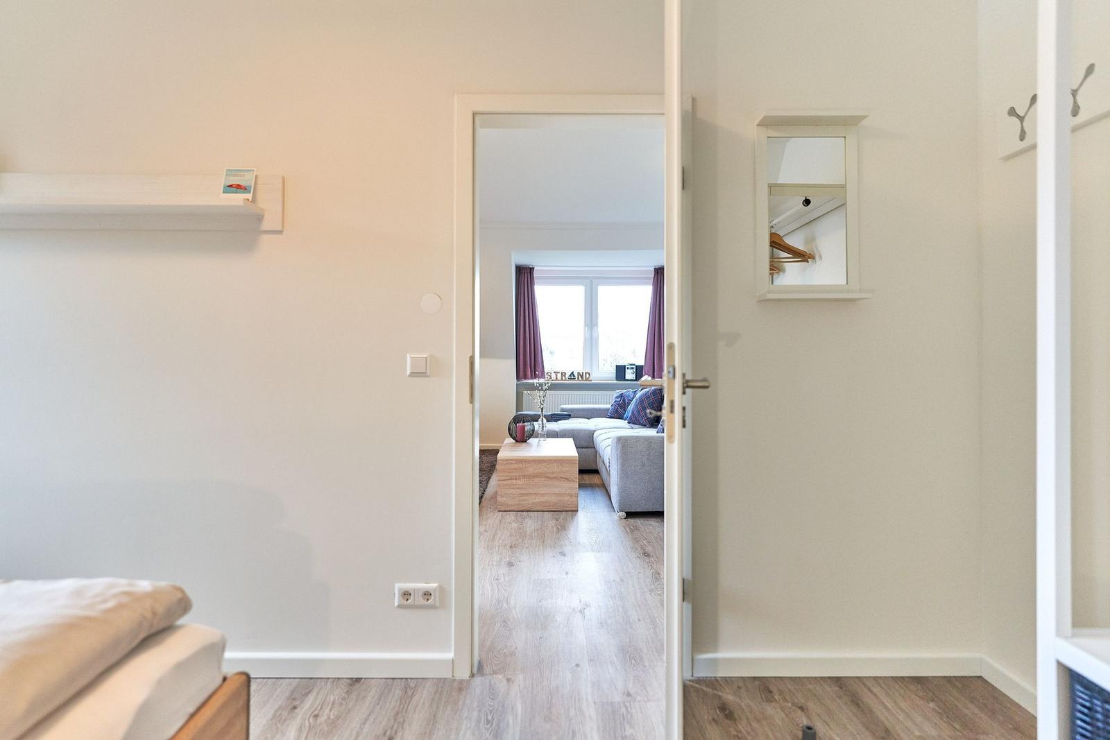 Schlafzimmer mit Blick auf Wohnzimmer mit Sofa und Fenster.