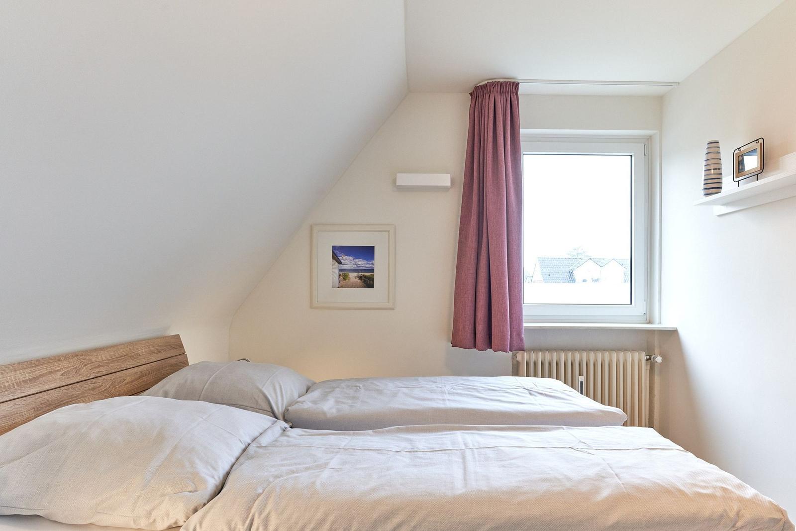 Schlafzimmer mit Doppelbett, Fenster und Dachschrägen.