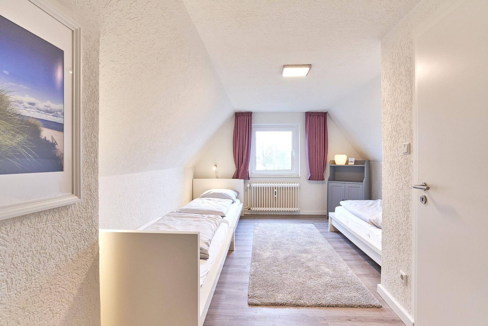 Zimmer mit zwei Betten, Fenster, Heizung und Teppichboden.