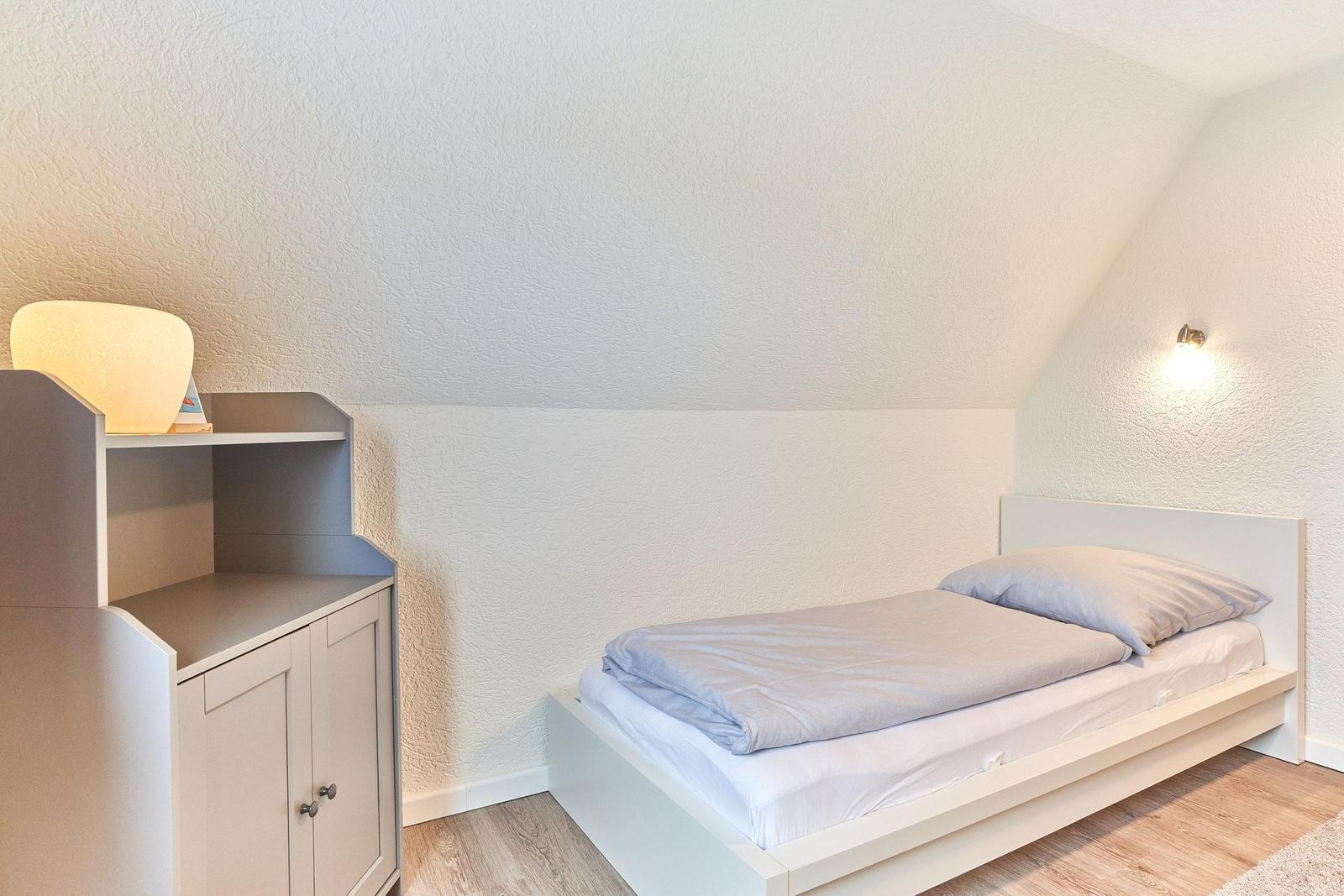 Ein Schlafzimmer mit einem Bett, einem Schrank und einer Wandlampe.