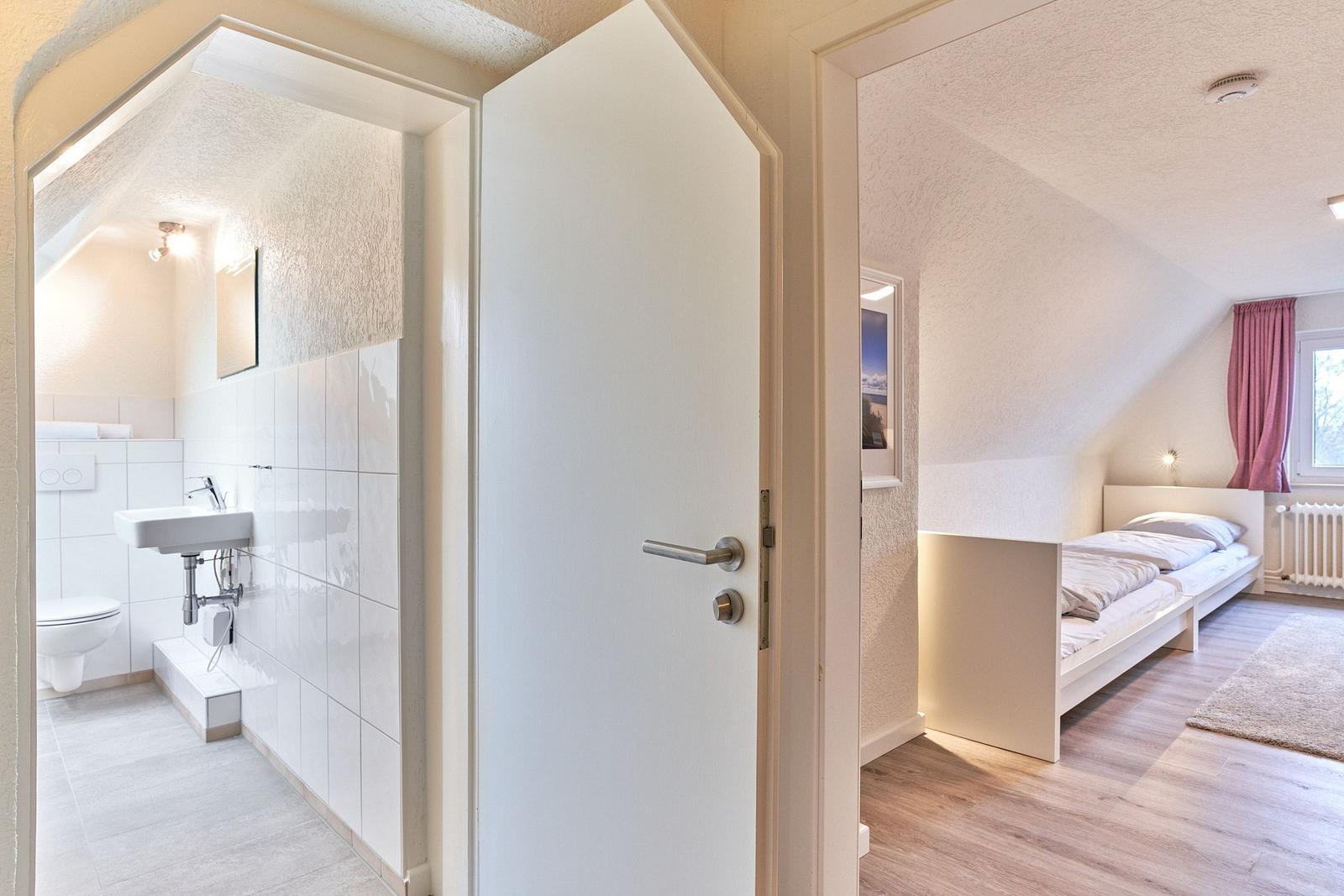 Schlafzimmer mit Doppelbett und Bad mit Waschbecken und Toilette.