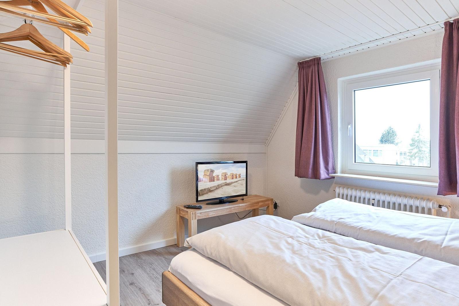 Zimmer mit Doppelbett, Fernseher und Fenster mit Blick nach draußen.