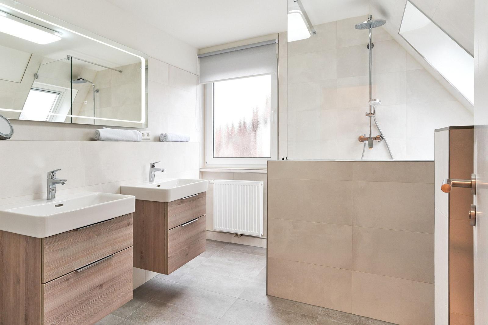 Badezimmer mit zwei Waschbecken, Dusche und Fenster.