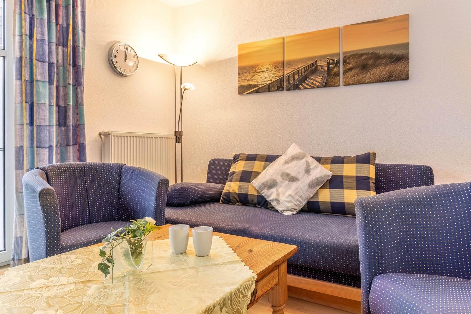 Wohnzimmer mit Sofa, Sesseln, Tisch und Wandbildern