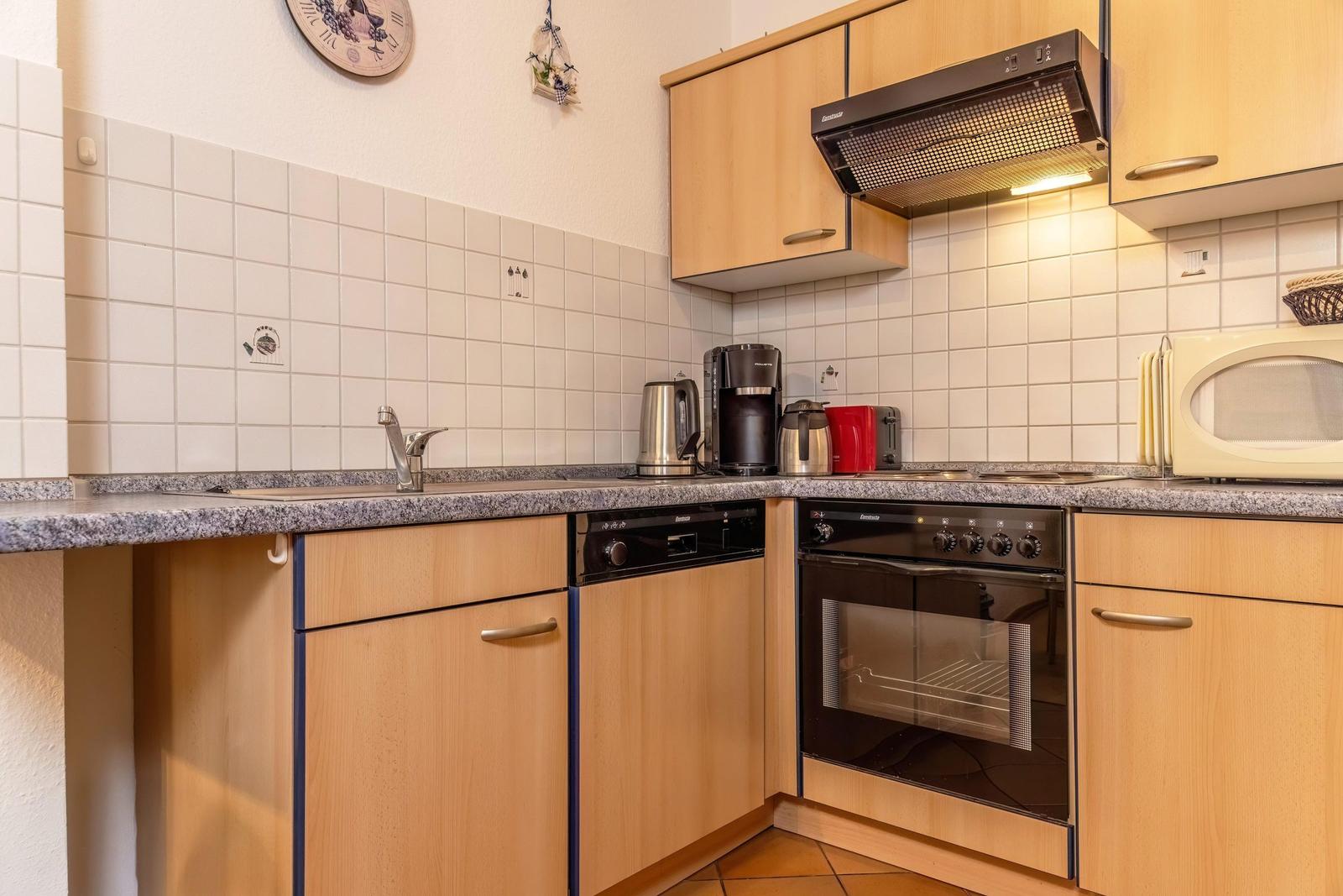 Küche mit Holzschränken, Spüle, Herd und Mikrowelle