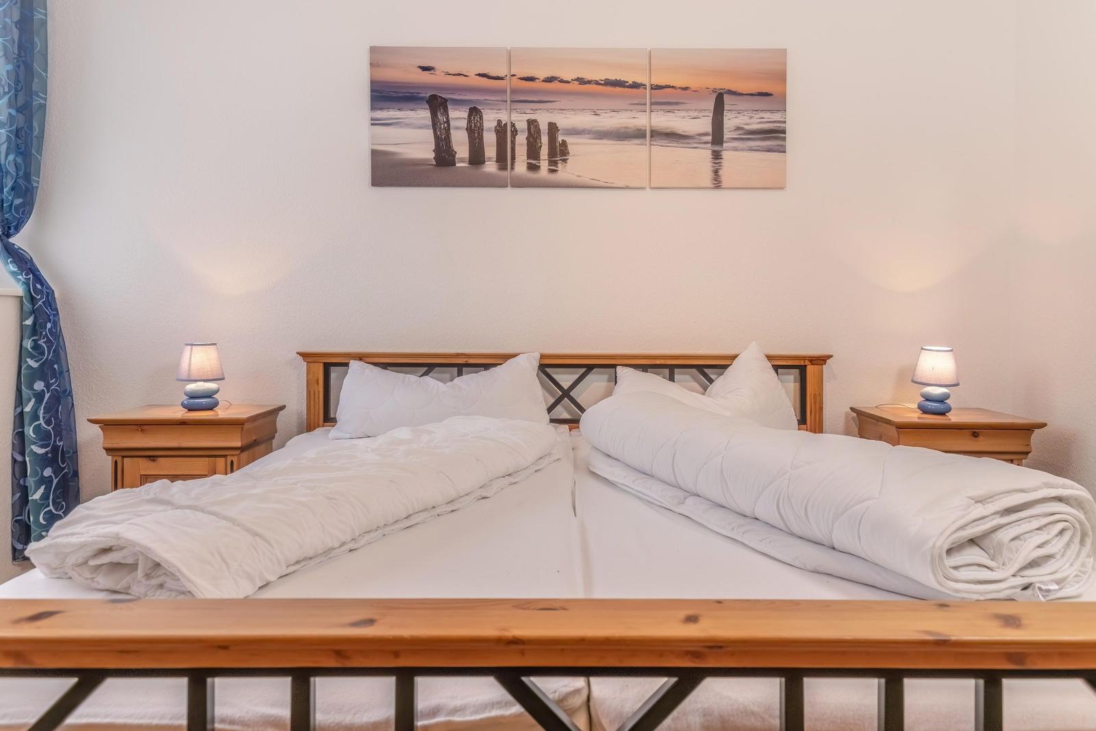 Zwei Betten mit weißen Bettwäschen und Holz-Nachtischen mit Lampen.