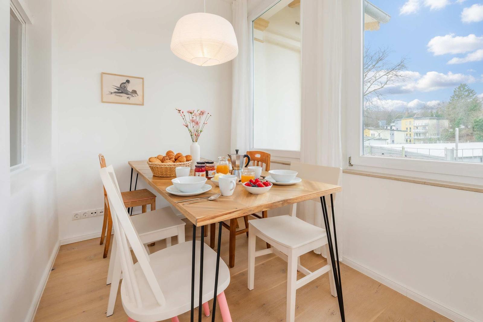 Esszimmer mit Holztisch, Stühlen und Blick auf die Straße.