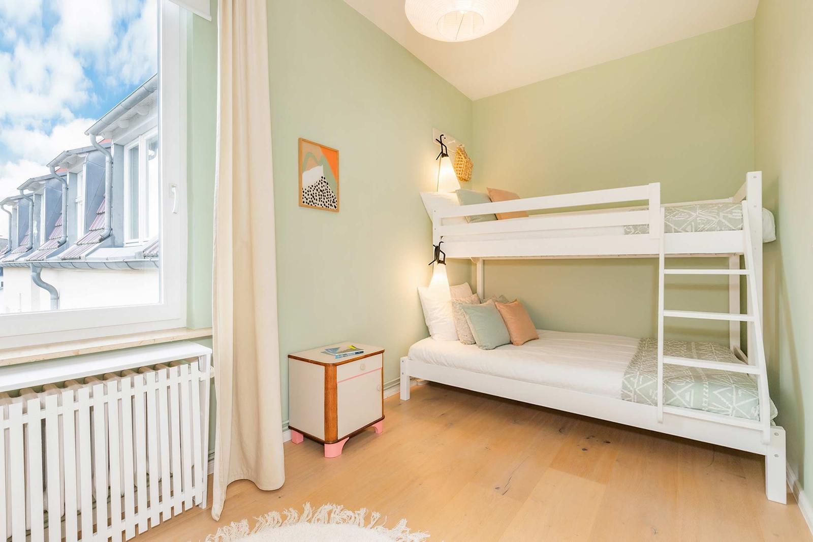 Zimmer mit Doppelstockbett, Fenster und Holzboden. Wandfarbe mintgrün.
