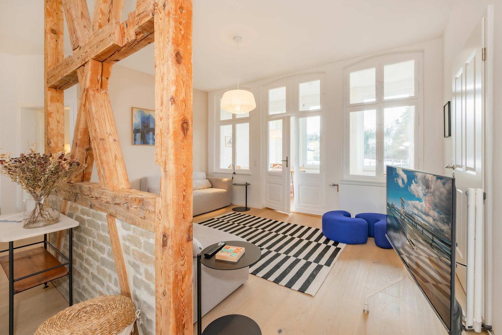 Wohnraum mit Holzrahmen, Sofa, TV und blauen Sitzkissen.
