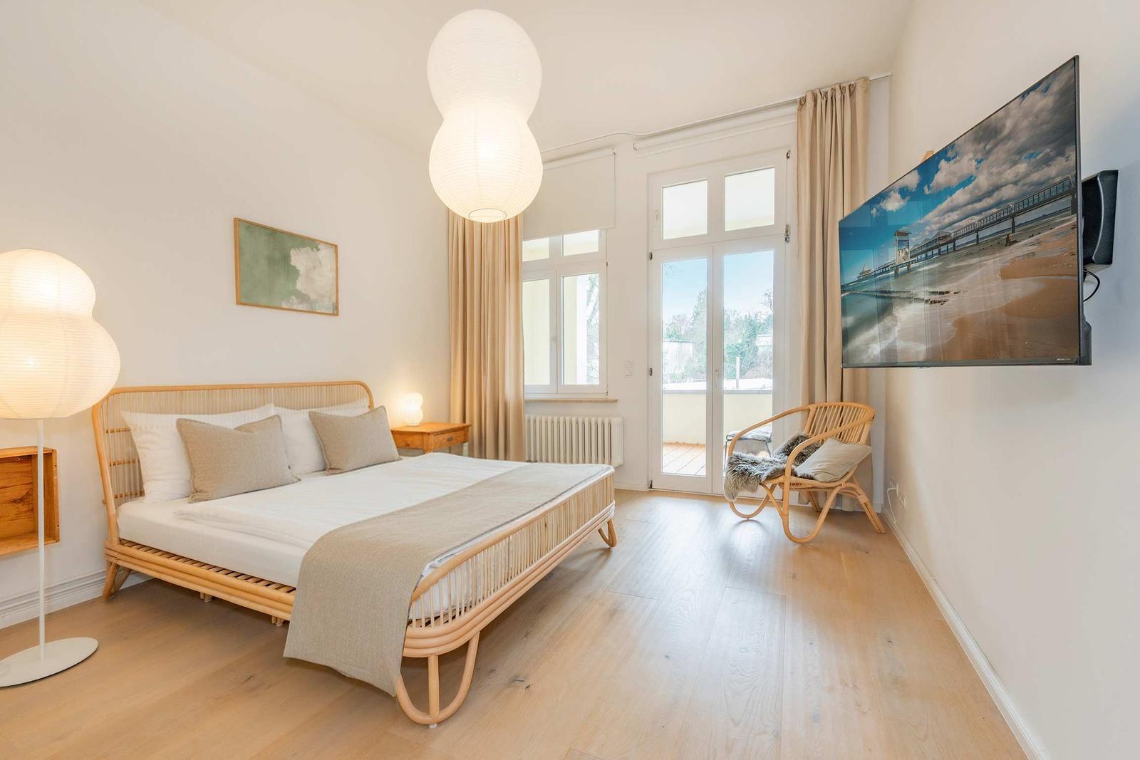 Schlafzimmer mit Bett, TV und Balkontür.