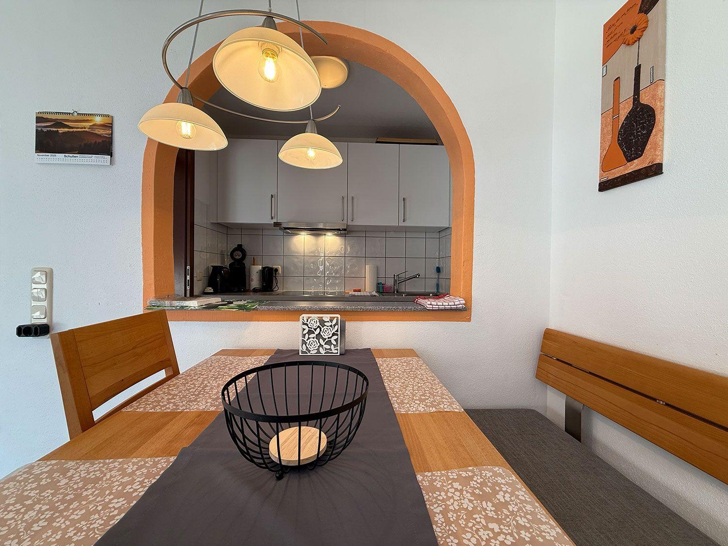 Essbereich mit Tisch, Stühlen und Blick in die Küche.