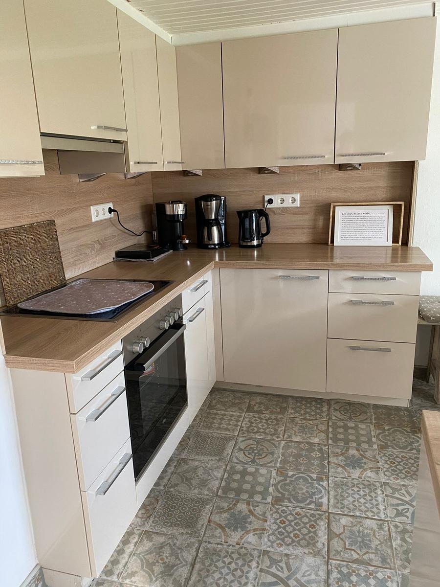 Küche mit hellen Schränken, Holzoberflächen und gemustertem Bodenbelag.