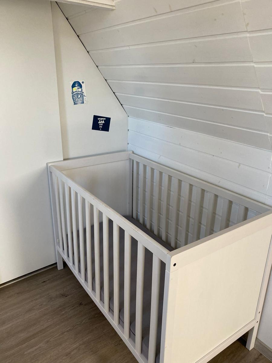 Kinderbett in einem Raum mit schräger Decke und Holzfußboden.