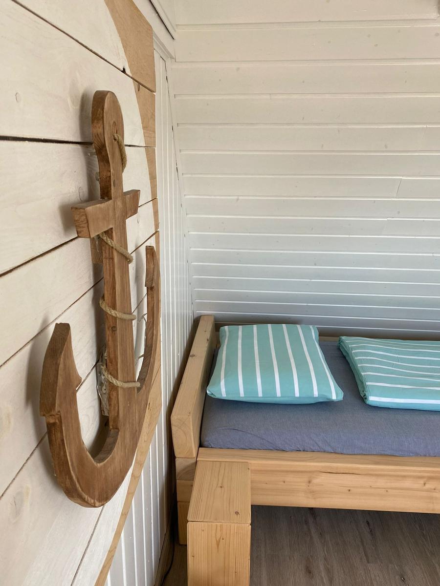 Hölzernes Bett mit Kissen und Wanddekoration in Form eines Ankers.