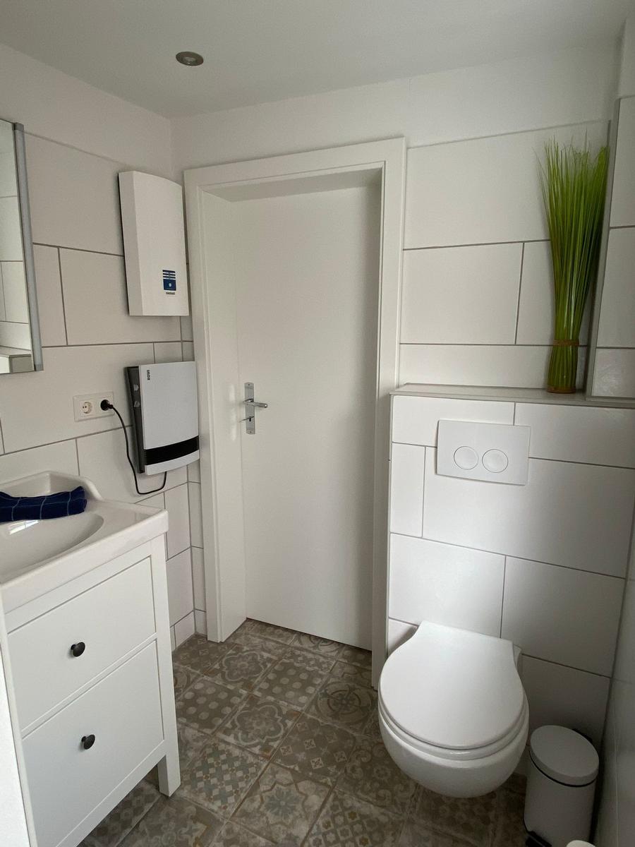 Badezimmer mit Toilette, Waschbecken und bodenfliesen.