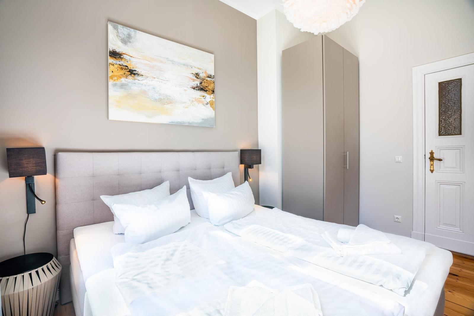 Schlafzimmer mit Bett, Kleiderschrank und Wandbild.