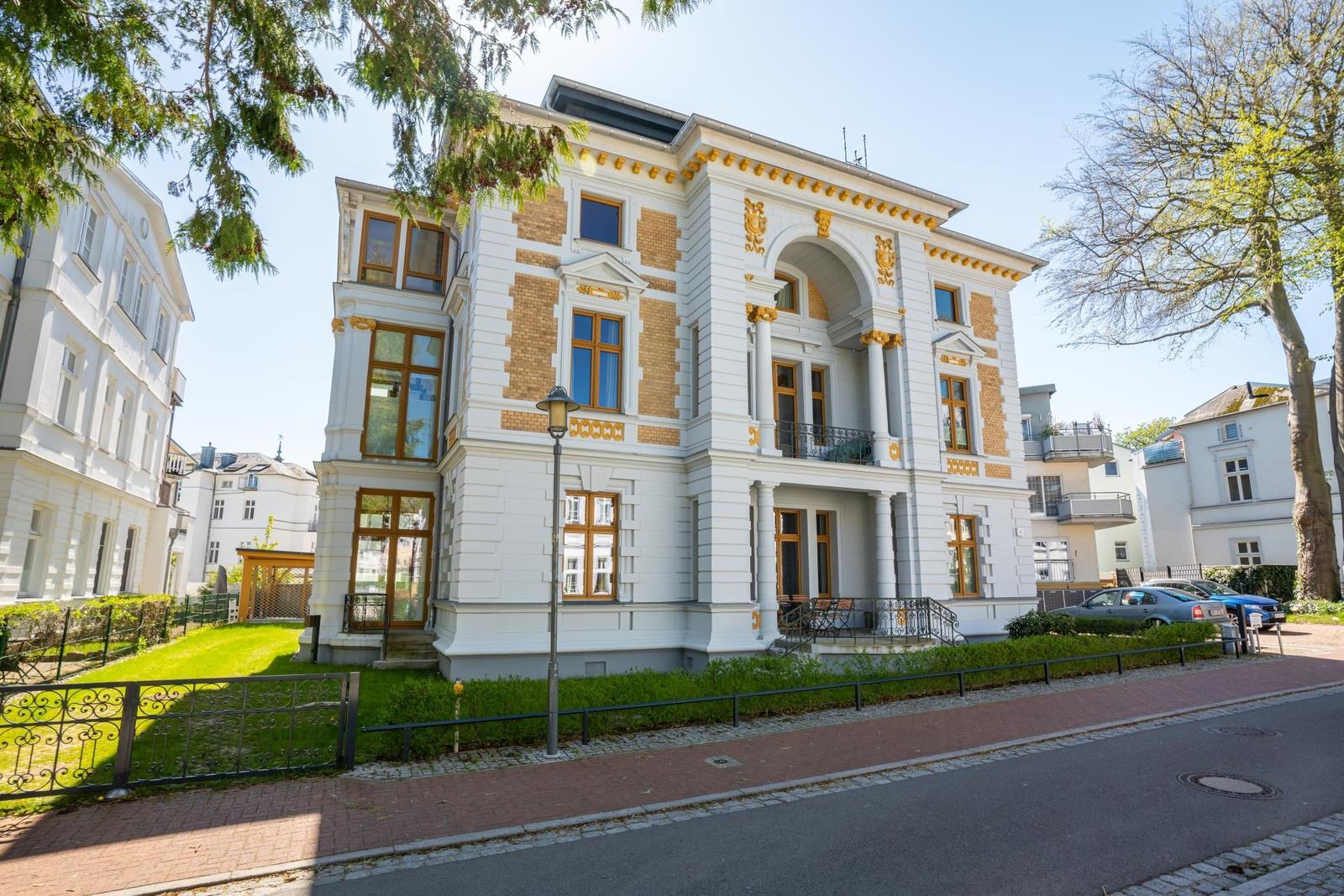 Elegantes Haus mit goldfarbenen Verzierungen und großzügigem Vorgarten.