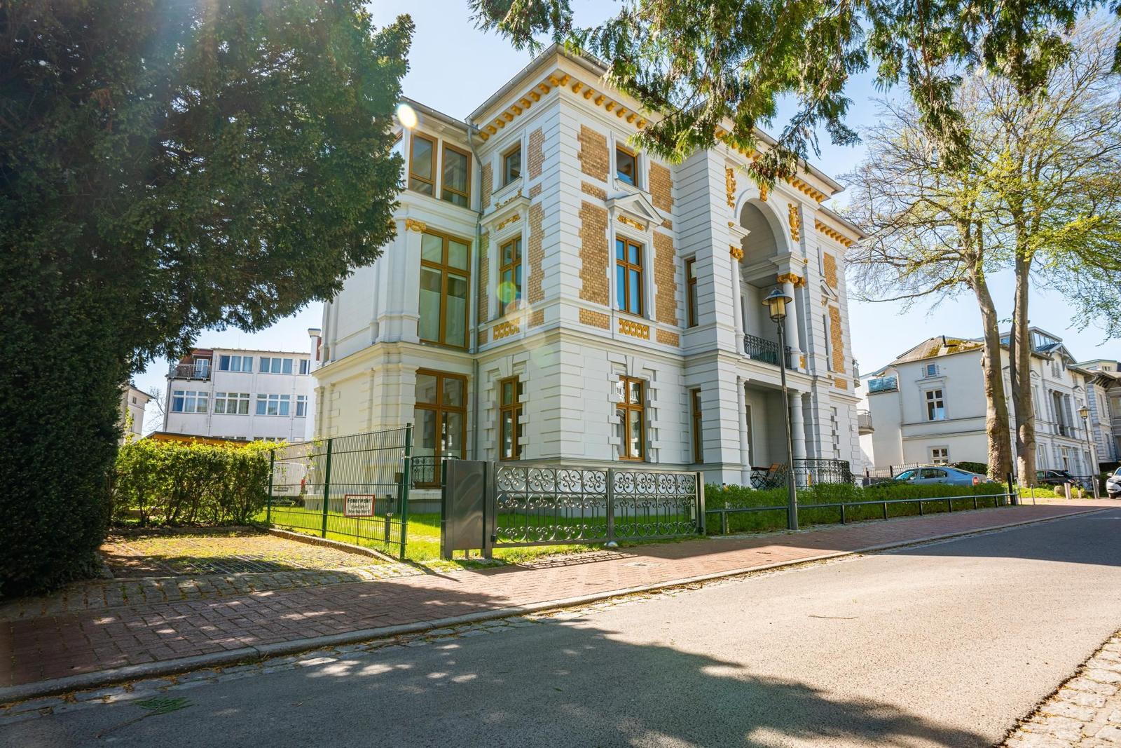 Historisches Gebäude mit weißen Wänden und goldenen Verzierungen an der Straße.
