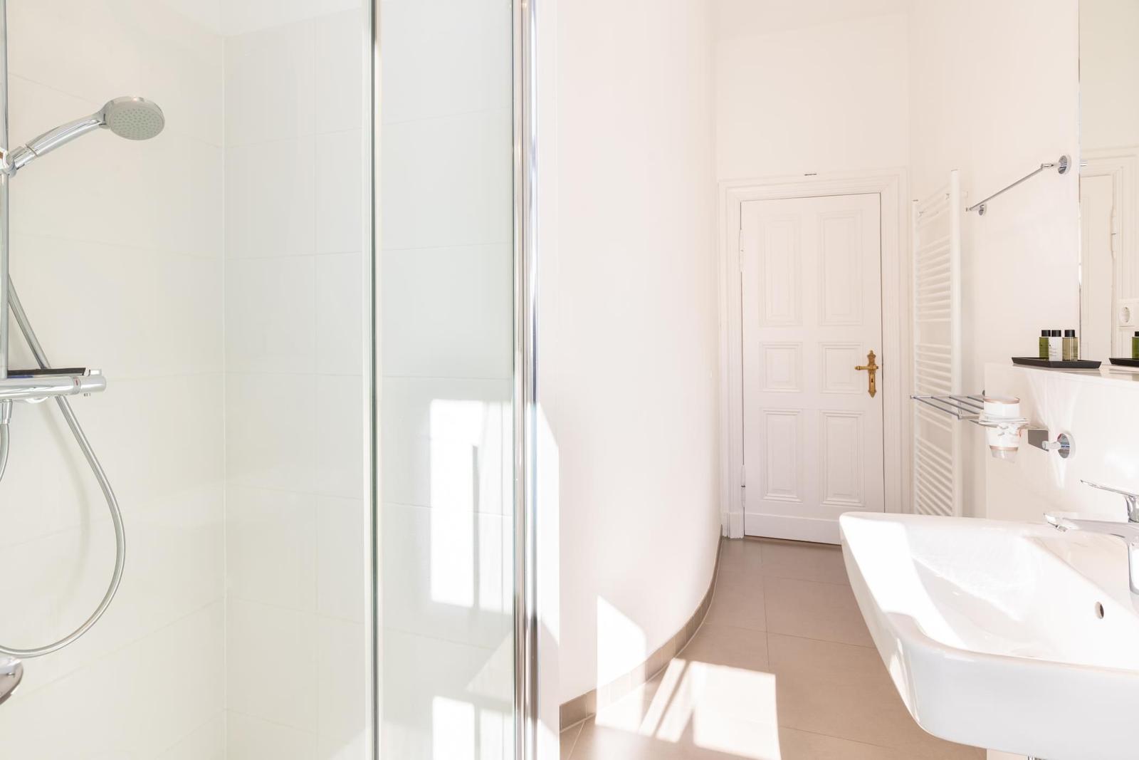 Badezimmer mit Dusche, Waschbecken und Heizkörper.