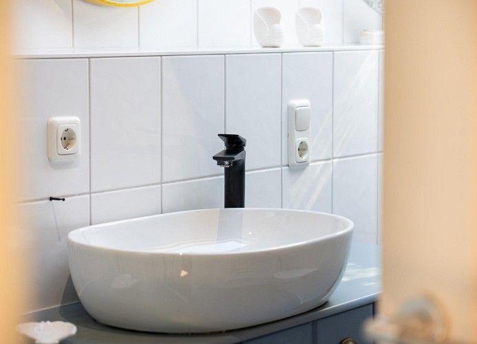 Waschbecken mit schwarzem Wasserhahn auf grauer Arbeitsplatte